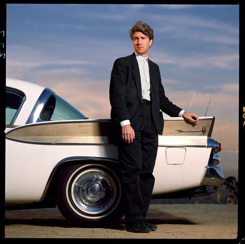 Director David Lynch stands outdoors in front of Packard vehicle in Los Angeles in 1986.